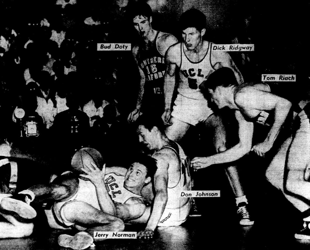 UCLA Bruins forward Jerry Norman (left) hits the floor to secure the ball during a Pacific Coast Conference Southern Division playoff game against the USC Trojans on March 5, 1951 